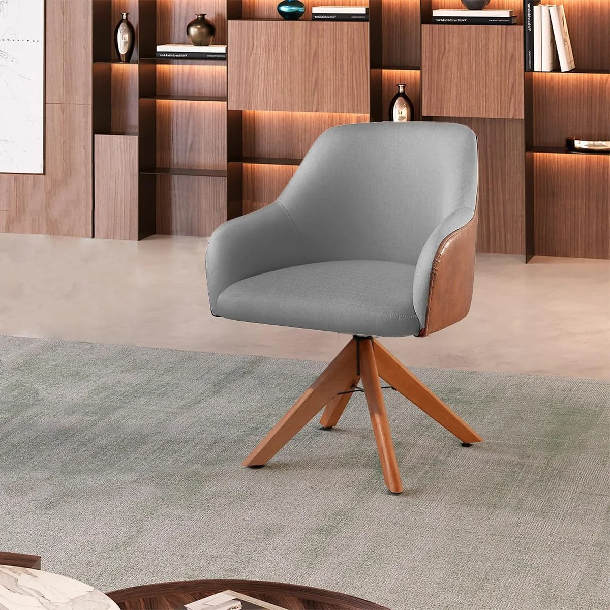 Poltrona Hera com base giratória de madeira, estofado em linho cinza com detalhe em couro, ideal para espaços pequenos.