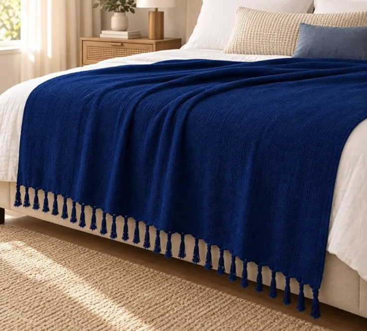 Manta de algodão azul com franjas sobre cama, mesmo modelo do sofá