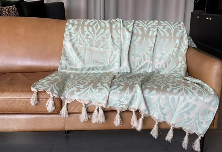 Xale jacquard verde água com dourado sobre sofá de couro caramelo